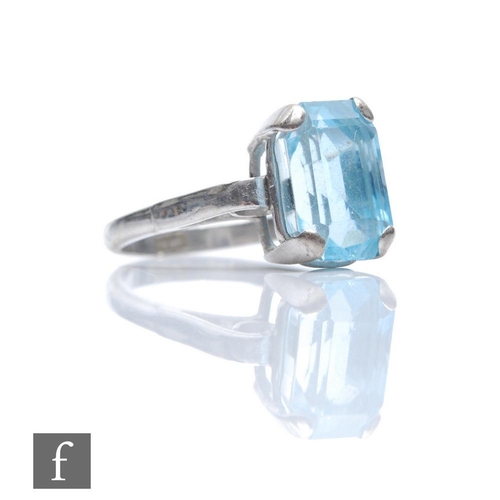 328 - An 18ct white gold single stone aquamarine ring, claw set emerald cut stone to scrolled shoulders, w... 