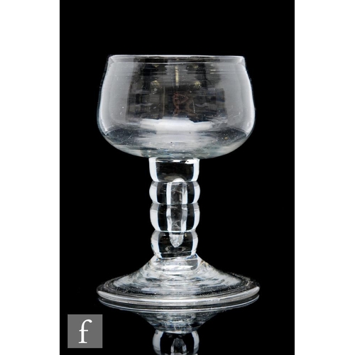 11 - An 18th Century drinking glass circa 1740, the ovoid bowl raised to a four section bobbin stem with ... 