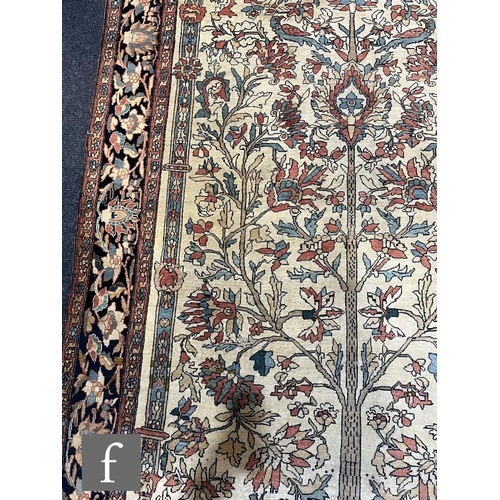1281 - An early 20th Century Persian 'Tree of Life' pattern rug, on an oatmeal ground within foliate patter... 