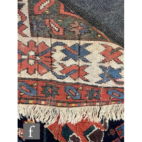 1280 - A mid 20th Century Kazak runner, the rug with repeat pattern medallions on a dark blue ground within... 