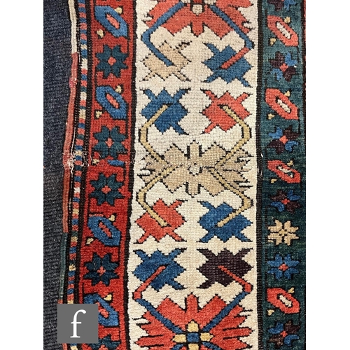1280 - A mid 20th Century Kazak runner, the rug with repeat pattern medallions on a dark blue ground within... 