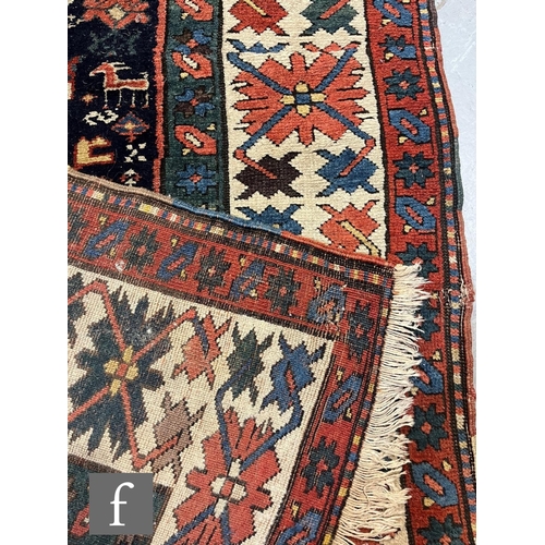 1280 - A mid 20th Century Kazak runner, the rug with repeat pattern medallions on a dark blue ground within... 