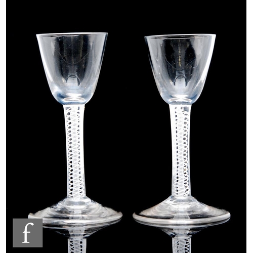 776 - A close pair of 18th Century drinking glasses, the round funnel bowls above a double series air twis... 