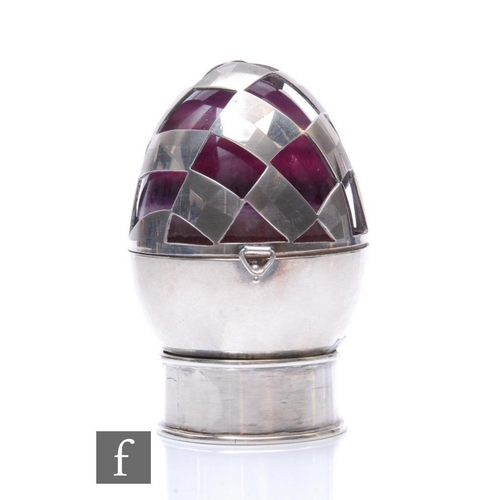 287 - A modern hallmarked silver pierced egg case encompassing a polished amethyst egg, all to a small cir... 