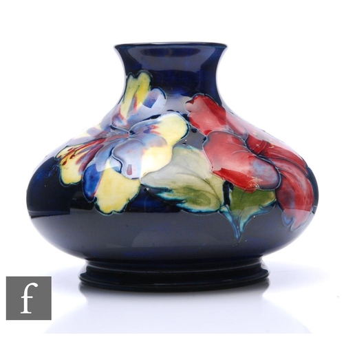 538 - A Moorcroft Hibiscus vase of squat form, the blue ground tubeline decorated with pink, purple and ye... 