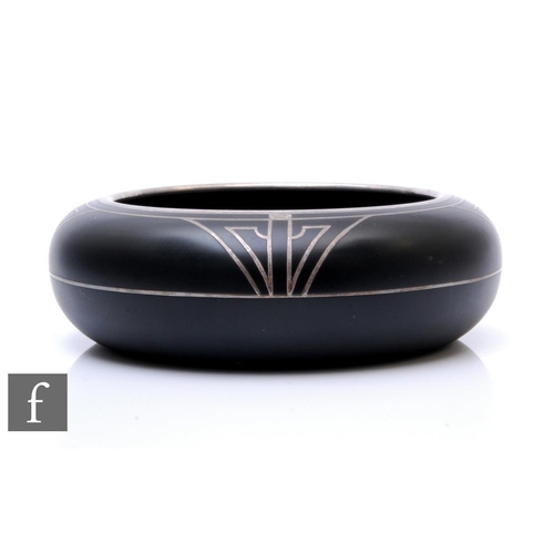 888 - A 1930s American Art Deco black glass bowl of shallow circular form with roll over rim, the exterior... 