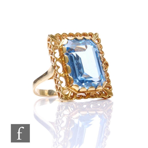 148 - A 9ct hallmarked single stone blue topaz ring, claw set emerald cut stone, length 17mm, to a pierced... 