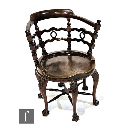 1000 - An early 20th Century mahogany swivel desk chair, the wavy lath back interspersed with pierced round... 