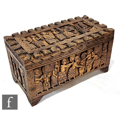 999 - An African hardwood linen or blanket chest, carved in deep relief with a procession of Benin style f... 