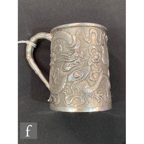 271 - An early 20th Century Chinese small silver tankard with embossed dragon decoration terminating in ba... 