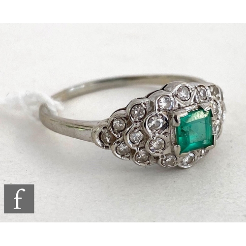 145 - An 14ct white gold emerald and diamond cluster ring, central square cut emerald to an oval diamond e... 