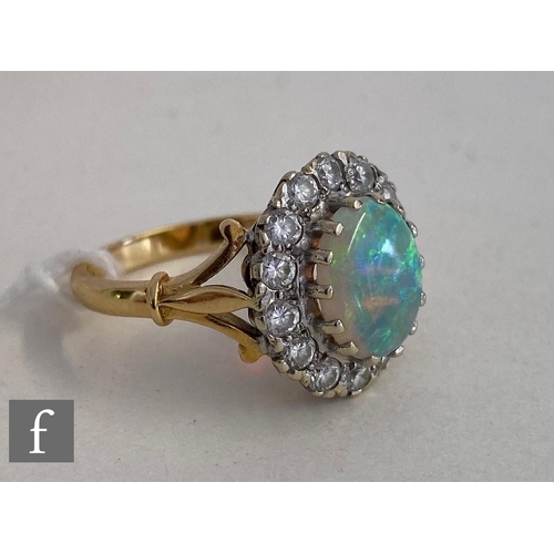 37 - An 18ct hallmarked opal and diamond cluster ring, central oval opal, length 10mm, within a border of... 