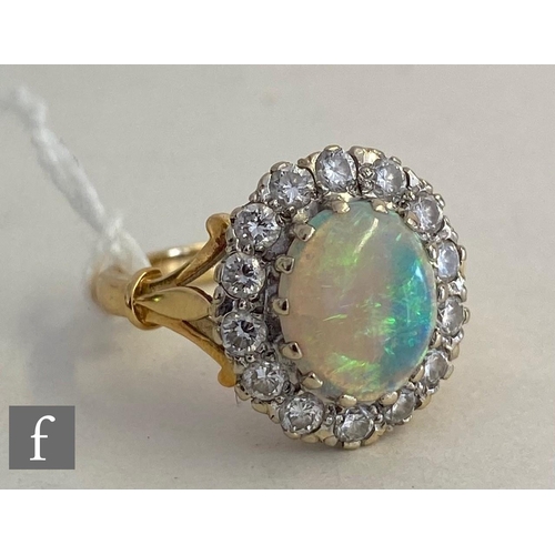 37 - An 18ct hallmarked opal and diamond cluster ring, central oval opal, length 10mm, within a border of... 