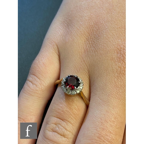 144 - An 18ct garnet and diamond cluster ring, central circular garnet within a twelve stone diamond borde... 