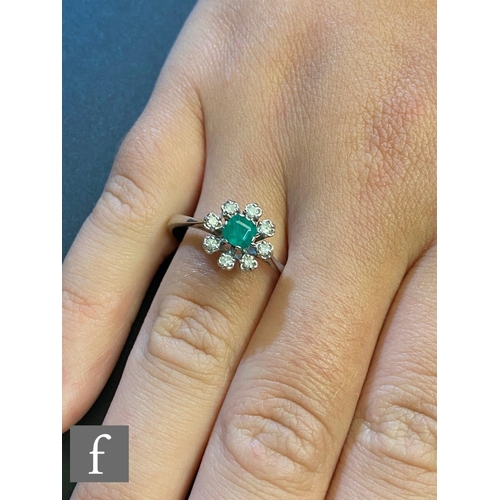 186 - A 14ct emerald and diamond flower head cluster ring, central emerald within a eight stone diamond su... 