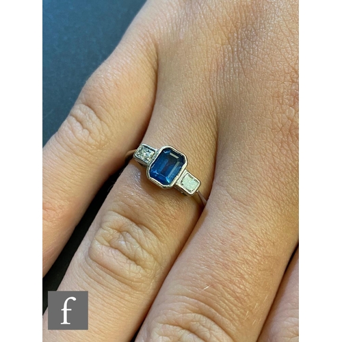 138 - A hallmarked 18ct white gold sapphire and diamond three stone ring, central emerald cut sapphire, le... 