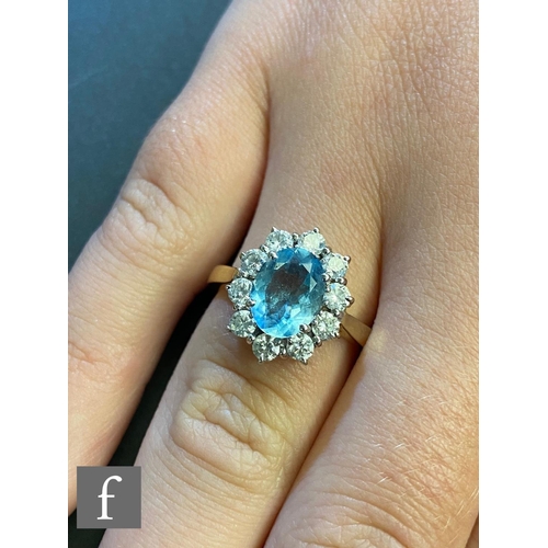 38 - An 18ct hallmarked aquamarine and diamond cluster ring, central oval aquamarine, length 9mm, within ... 