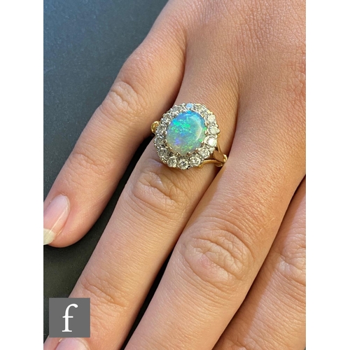 37 - An 18ct hallmarked opal and diamond cluster ring, central oval opal, length 10mm, within a border of... 