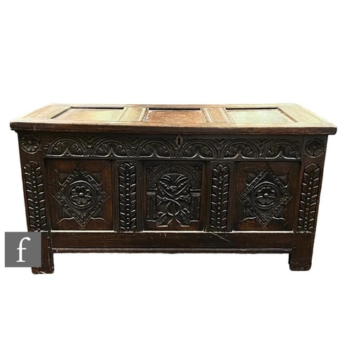 1093 - An 18th Century oak coffer, with triple fielded front panel, heavily carved with rosettes and with f... 