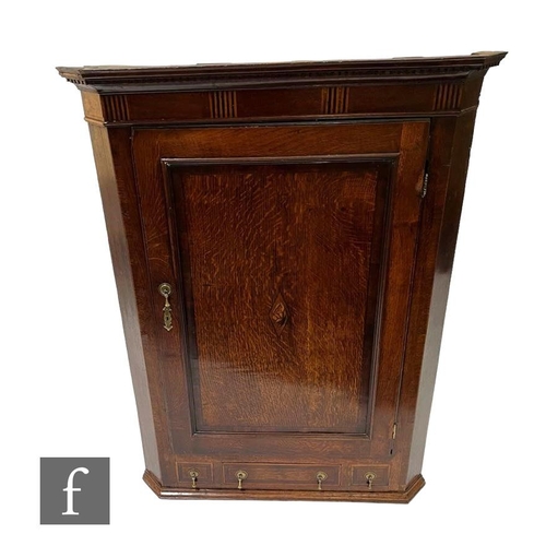 1105 - A George III oak flat-fronted wall hanging corner cupboard, with mahogany cross-banded frieze above ... 