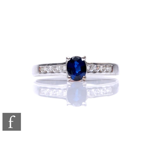 A 14ct white gold sapphire and diamond ring, central oval sapphire flanked by diamond set shoulders, weight 2g, ring size L.
