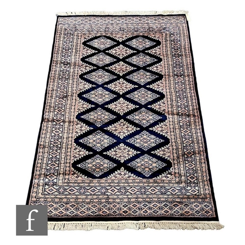 1111 - Two contemporary Bokhara rugs, each decorated with diamond shaped medallions on a dark blue ground, ... 