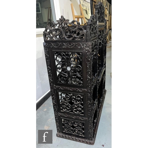 1094 - A late 19th Century Anglo Indian carved harwood/Padouk floorstanding cabinet, the pierced top rail o... 