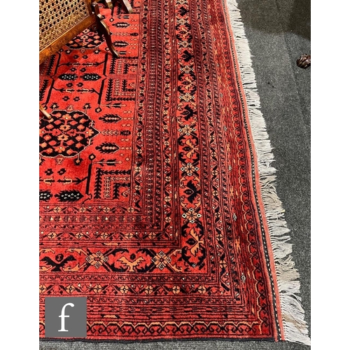 1114 - A modern Afghan Mohammadi carpet, with a repeat pattern of blue medallions on a red and terracotta c... 