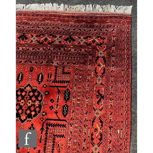 1114 - A modern Afghan Mohammadi carpet, with a repeat pattern of blue medallions on a red and terracotta c... 