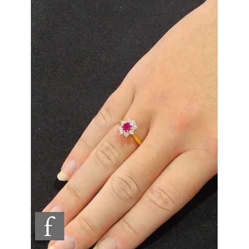 629 - An 18ct hallmarked ruby and diamond cluster ring, central oval ruby, length 5mm, within a border of ... 