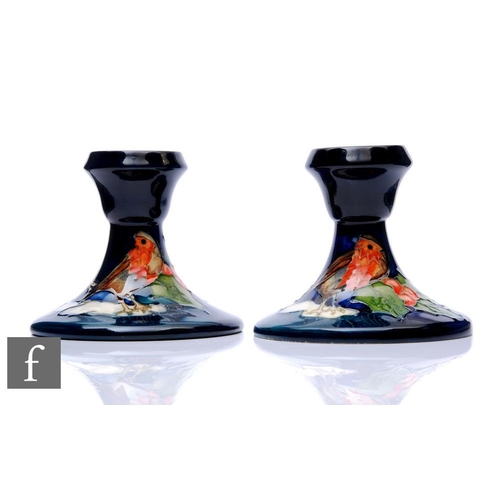 110 - Sally Tuffin - Moorcroft Pottery - A pair of candlesticks decorated in the Robins pattern with a tub... 