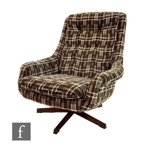 779 - Unknown designer - A 1970s swivel armchair in checked cloth upholstery, over a simulated wooden base... 