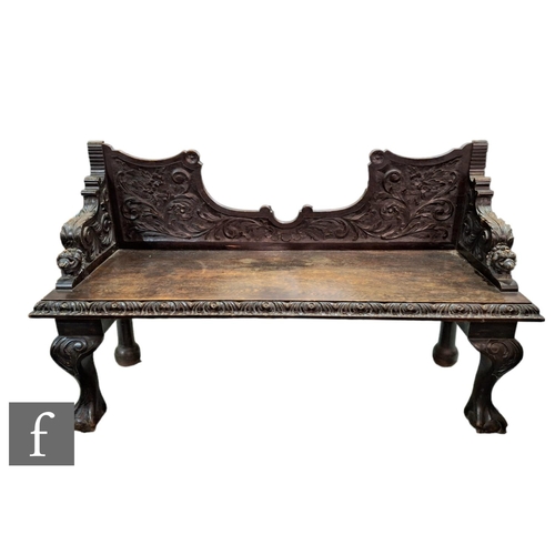 629 - A Victorian ebonised carved oak hall seat, panelled back, swept arms to lion masks, on claw and ball... 