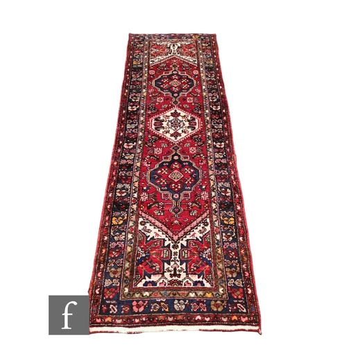 630 - A Hamadan style runner, a central lozenge pole medallion on a deep red ground within a multi floral ... 