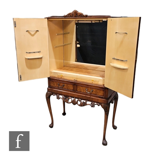 623 - A 1950s walnut veneered cocktail cabinet, the mirrored interior enclosed by a pair of doors over two... 