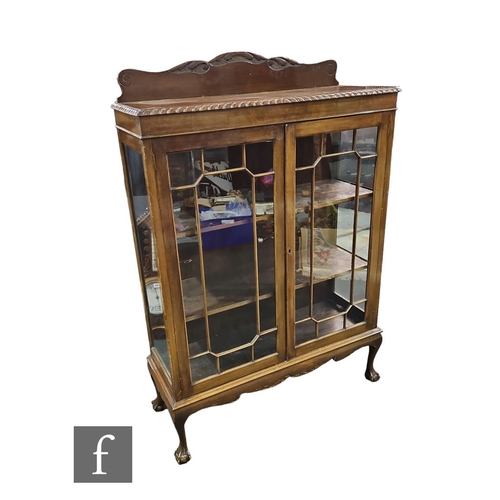 627 - An Edwardian mahogany display cabinet enclosed by a pair of bar glazed doors below a gadrooned edge ... 