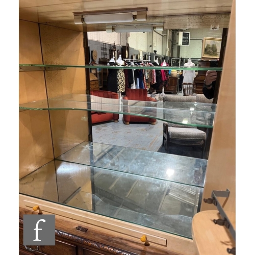 623 - A 1950s walnut veneered cocktail cabinet, the mirrored interior enclosed by a pair of doors over two... 