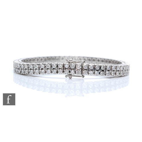 An 18ct white gold double row diamond tennis bracelet comprising two rows of fifty eight brilliant cut claw set diamonds, total weight approximately 5.8ct, weight 37.5g, length 18cm, terminating in tongue and box fastener, boxed.