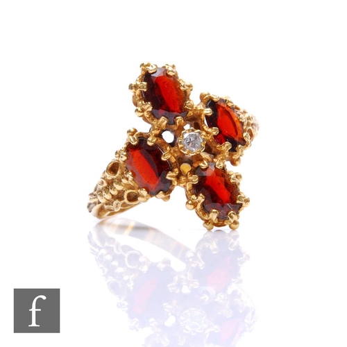 324 - An 18ct hallmarked garnet and diamond ring, central diamond within four oval claw set garnets, weigh... 