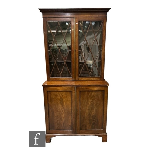 493 - A George III mahogany bookcase enclosed by a pair of diamond bar glazed doors below a fluted cornice... 