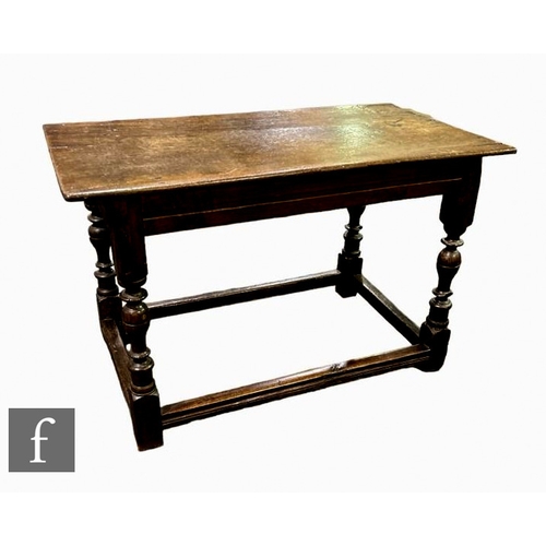 513 - An 18th Century oak centre table, the plank top over a line detailed frieze on turned block legs uni... 