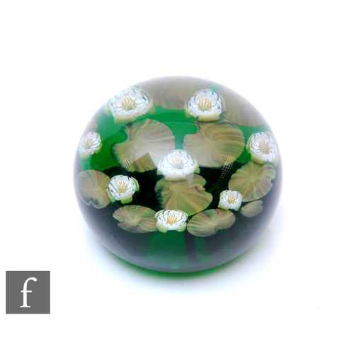 854 - A contemporary Twists Glass paperweight, of domed form and internally decorated with eight white wat... 