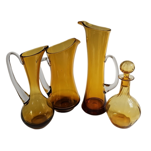 818 - A collection of three Whitefriars golden amber glass jugs, to include a tall slender waisted example... 