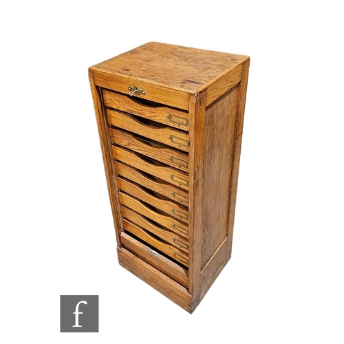 528A - A 1930s oak filing cabinet, the interior enclosed by a tambour shutter door, height 109cm x depth 37... 