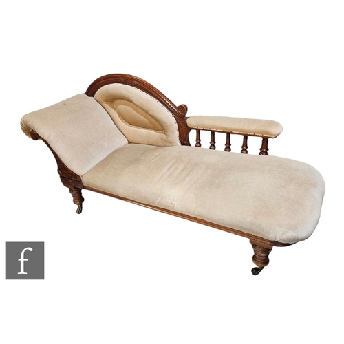 530A - An Edwardian carved mahogany scroll end chaise longue with spindle rail back on turned legs, upholst... 