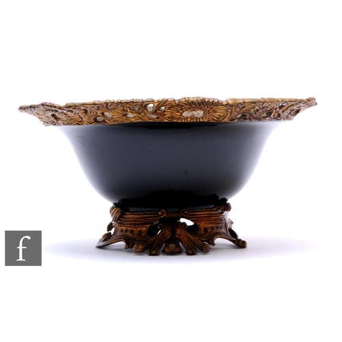 301 - A mid 20th Century black glazed circular fruit bowl with pierced scroll floret border on scroll acan... 