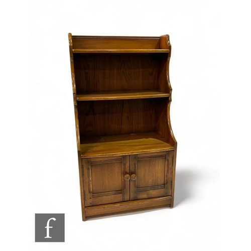 448 - A small Ercol waterfall bookcase, the shelves above a two door cupboard, height 111cm x depth 33cm x... 