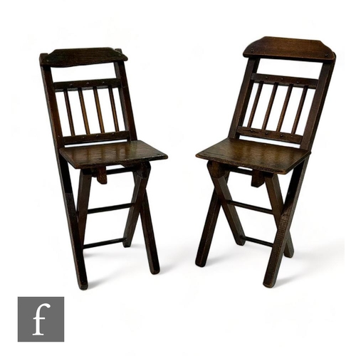 464 - A pair of 19th Century oak child's folding chairs, spindle backs below a shaped top rail over a bras... 