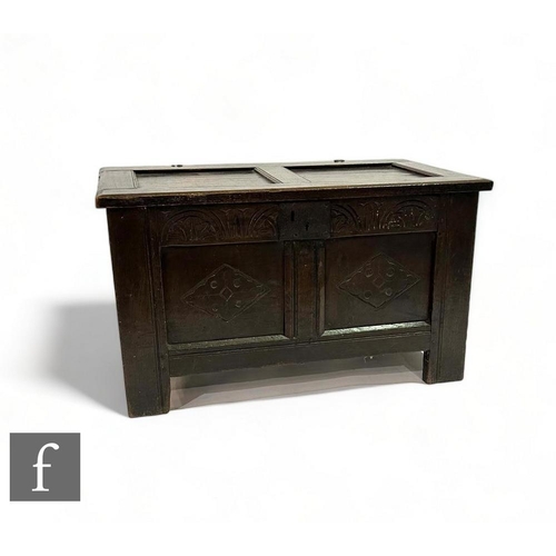 485 - A small 18th Century carved oak coffer, the twin hinged panel top over a diamond lozenge front, on s... 