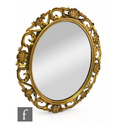 510 - A 20th Century oval wall mirror framed with scallop and scroll pierced border, 82cm x 68cm.